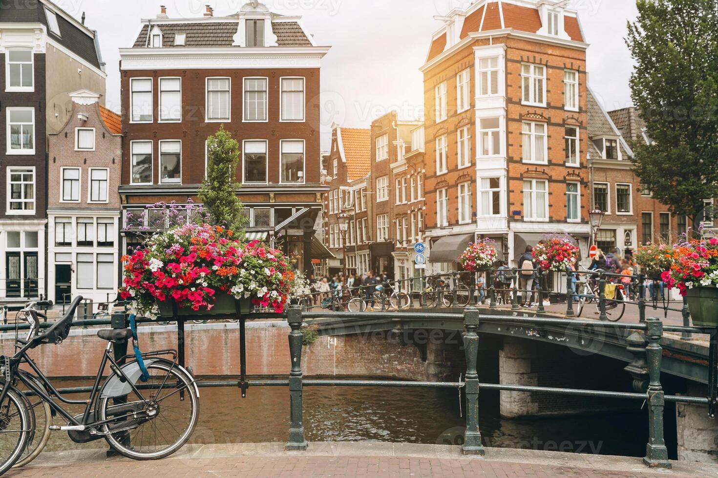 Old bicycle on the bridge in Amsterdam, Netherlands against a canal during summer sunny day. Postcard iconic view. Tourism concept. photo
