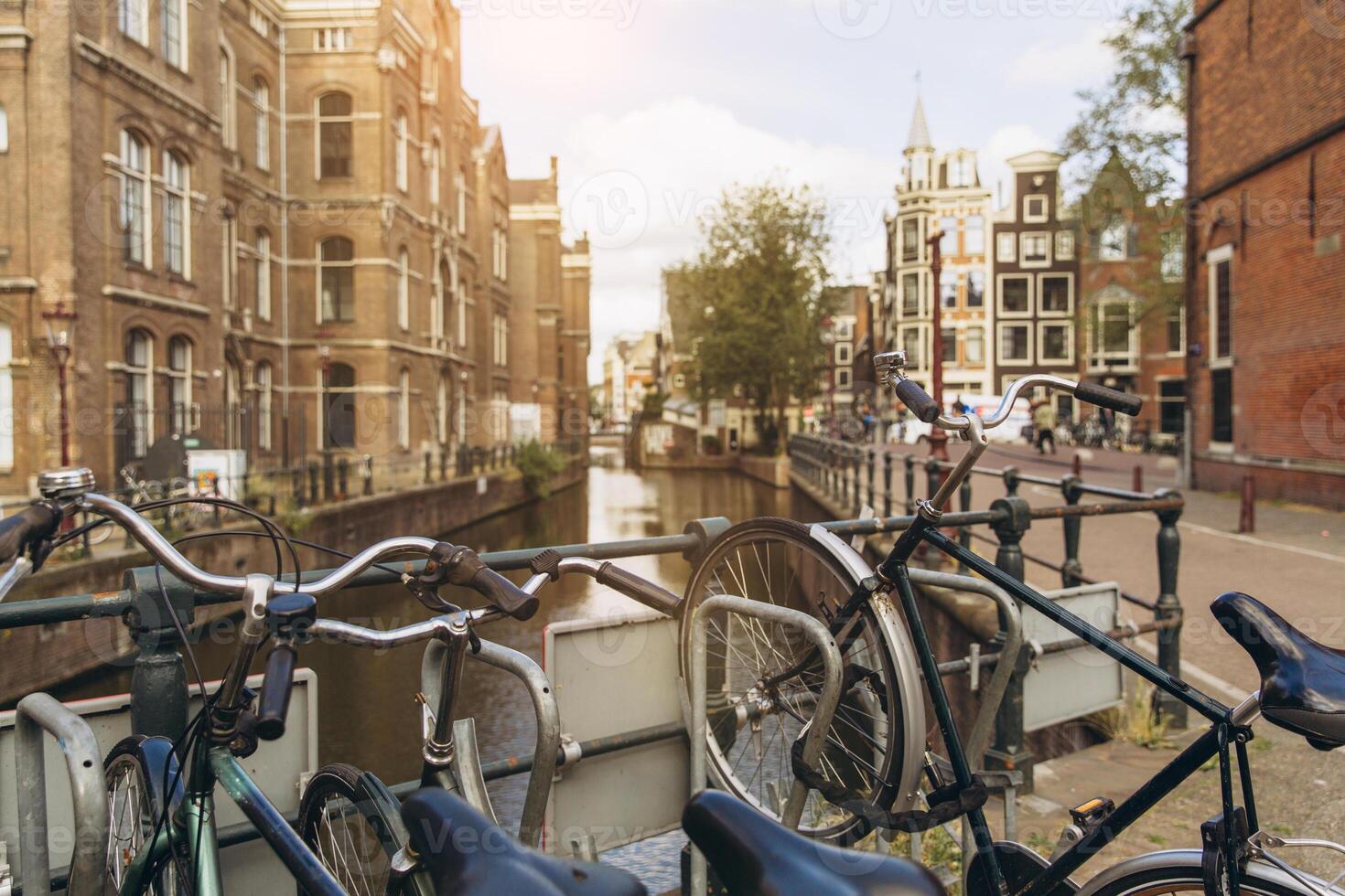 Old bicycle on the bridge in Amsterdam, Netherlands against a canal during summer sunny day. Postcard iconic view. Tourism concept. photo
