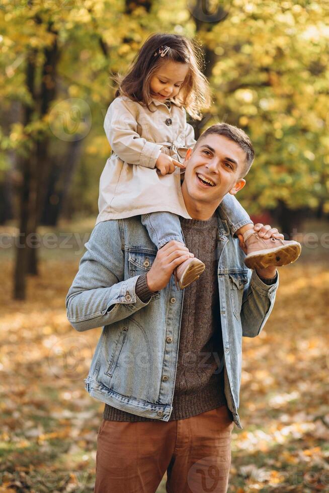 Happy dad and little daughter walking in autumn park, father's day concept photo
