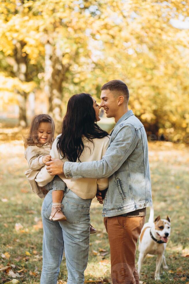 Happy young family walks and plays with a dog in the autumn park photo