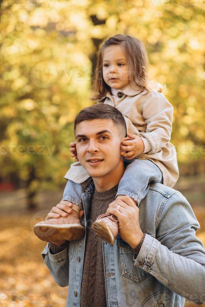 Happy dad and little daughter walking in autumn park, father's day concept photo