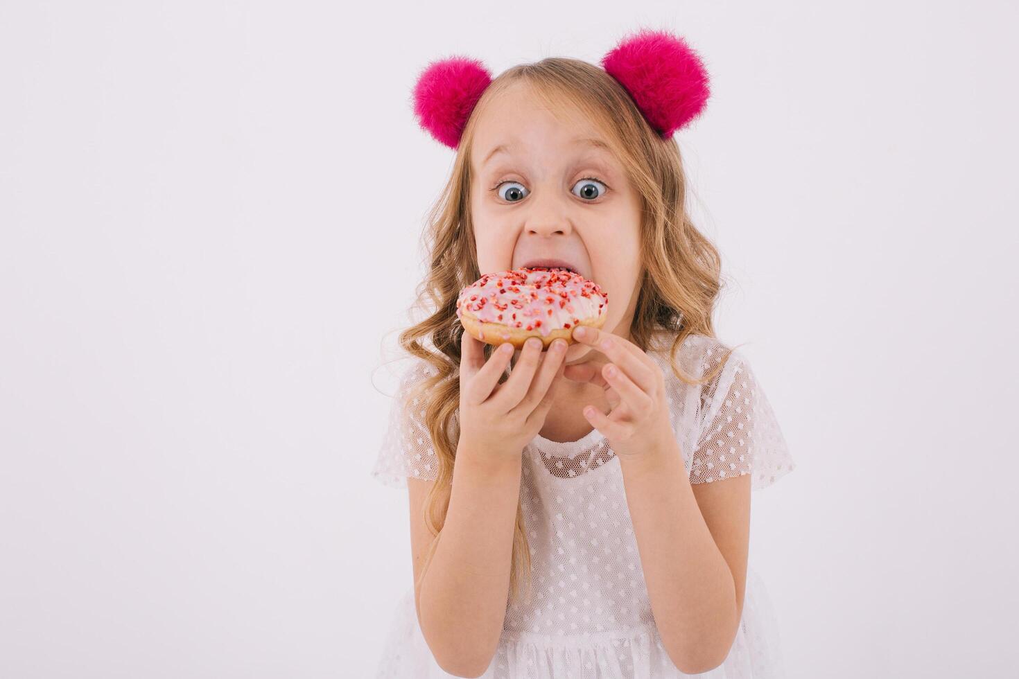 Funny little girl eating a donut on a white background photo