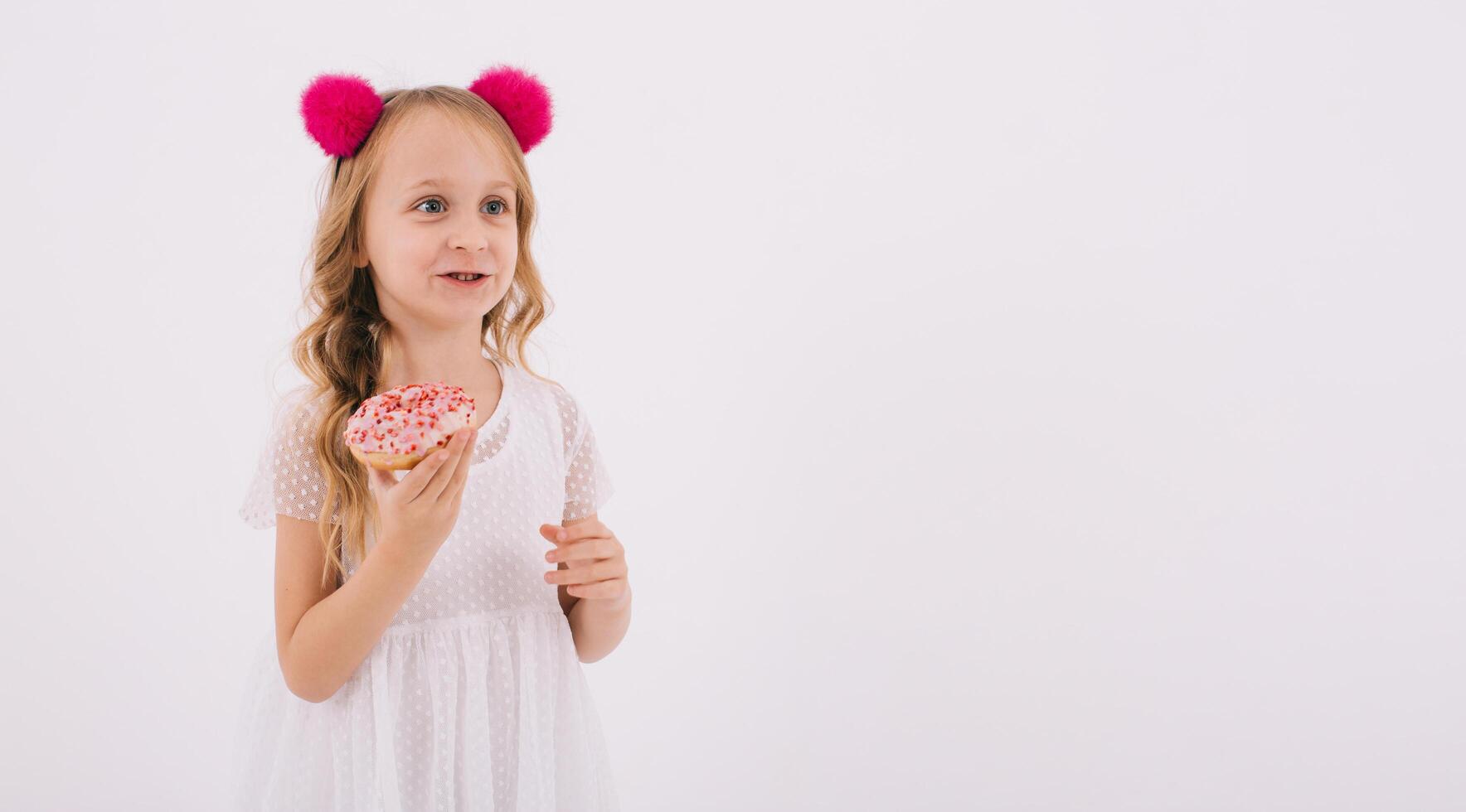 Funny little girl eating a donut on a white background photo
