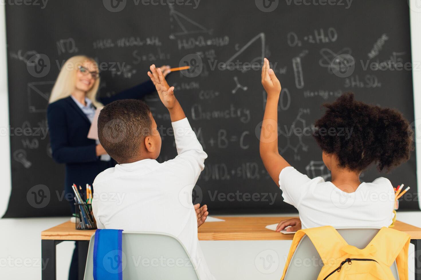 A female teacher teaches schoolchildren at the blackboard in the classroom. International team. Back to school. photo