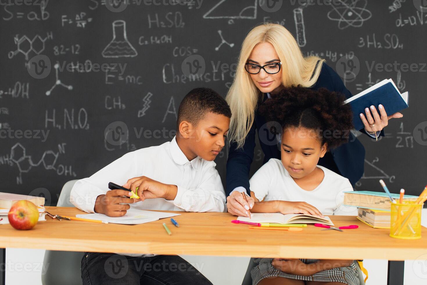 A female teacher helps school children solve problems at school. International team. Back to school. photo