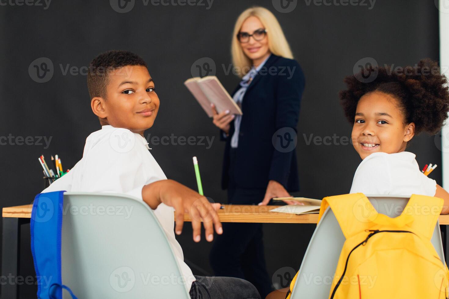 A girl and a boy, African-American school children, solve problems with the teacher during a lesson. Back to school. photo
