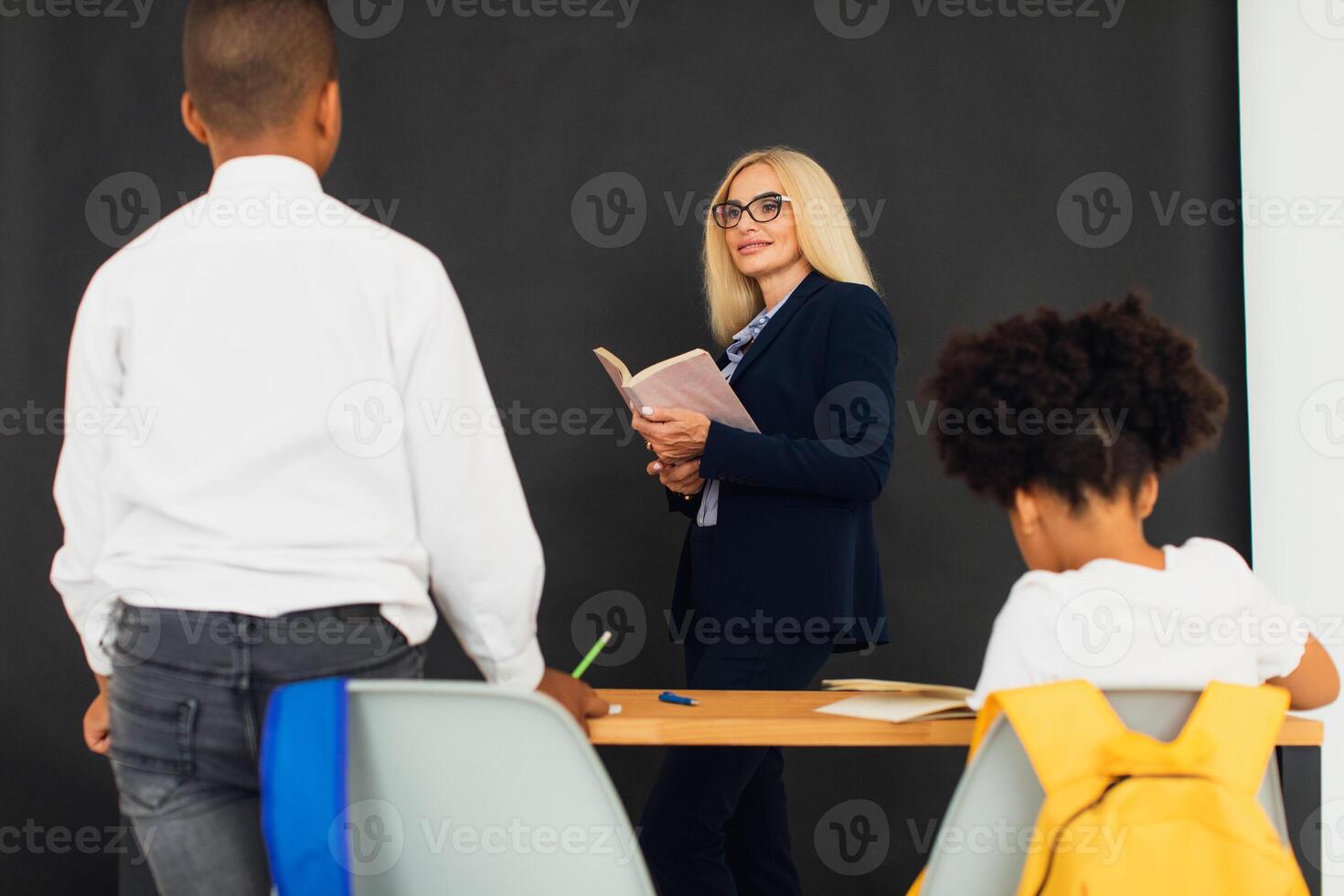 A girl and a boy, African-American school children, solve problems with the teacher during a lesson. Back to school. photo