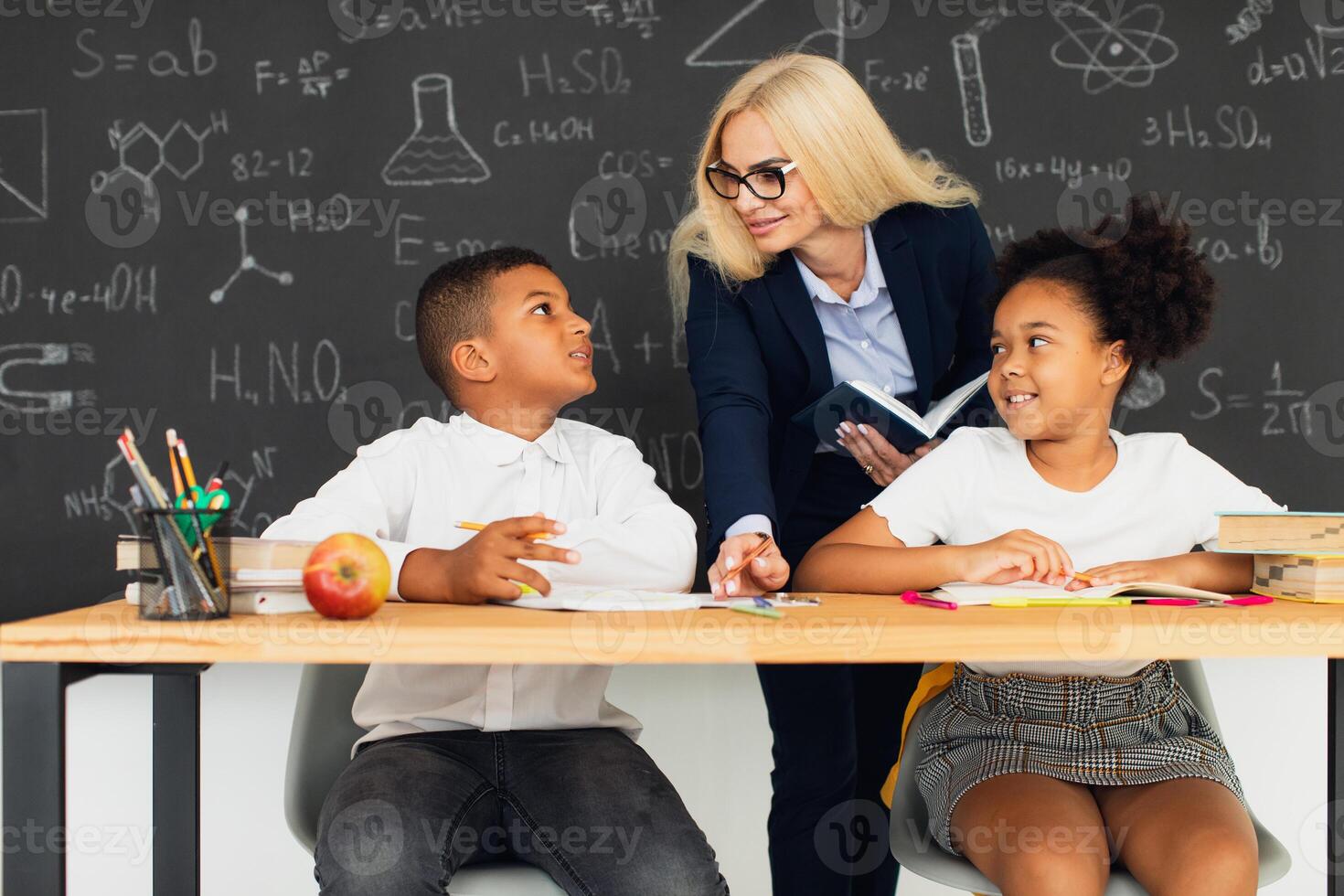 A female teacher helps school children solve problems at school. International team. Back to school. photo