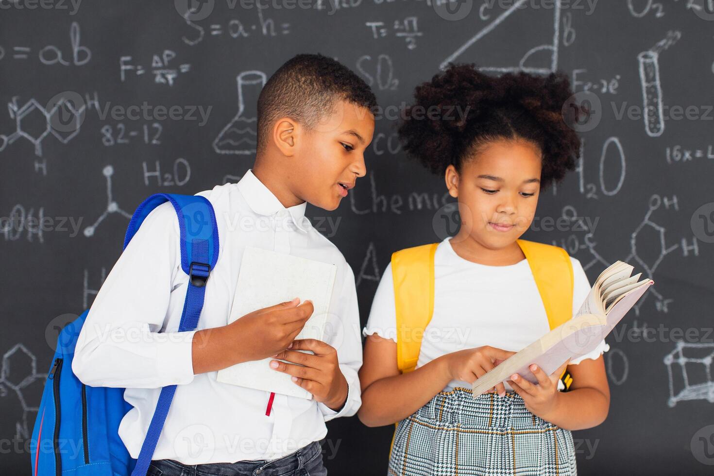 African American schoolgirl and schoolboy solving problems near school board, back to school concept photo