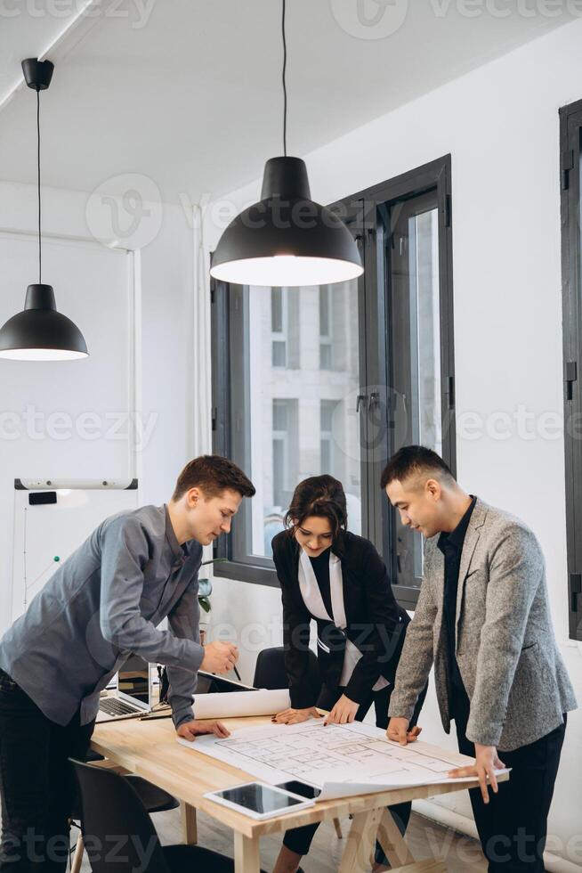 Close-up shot of group of architects drawing building plan together at office photo