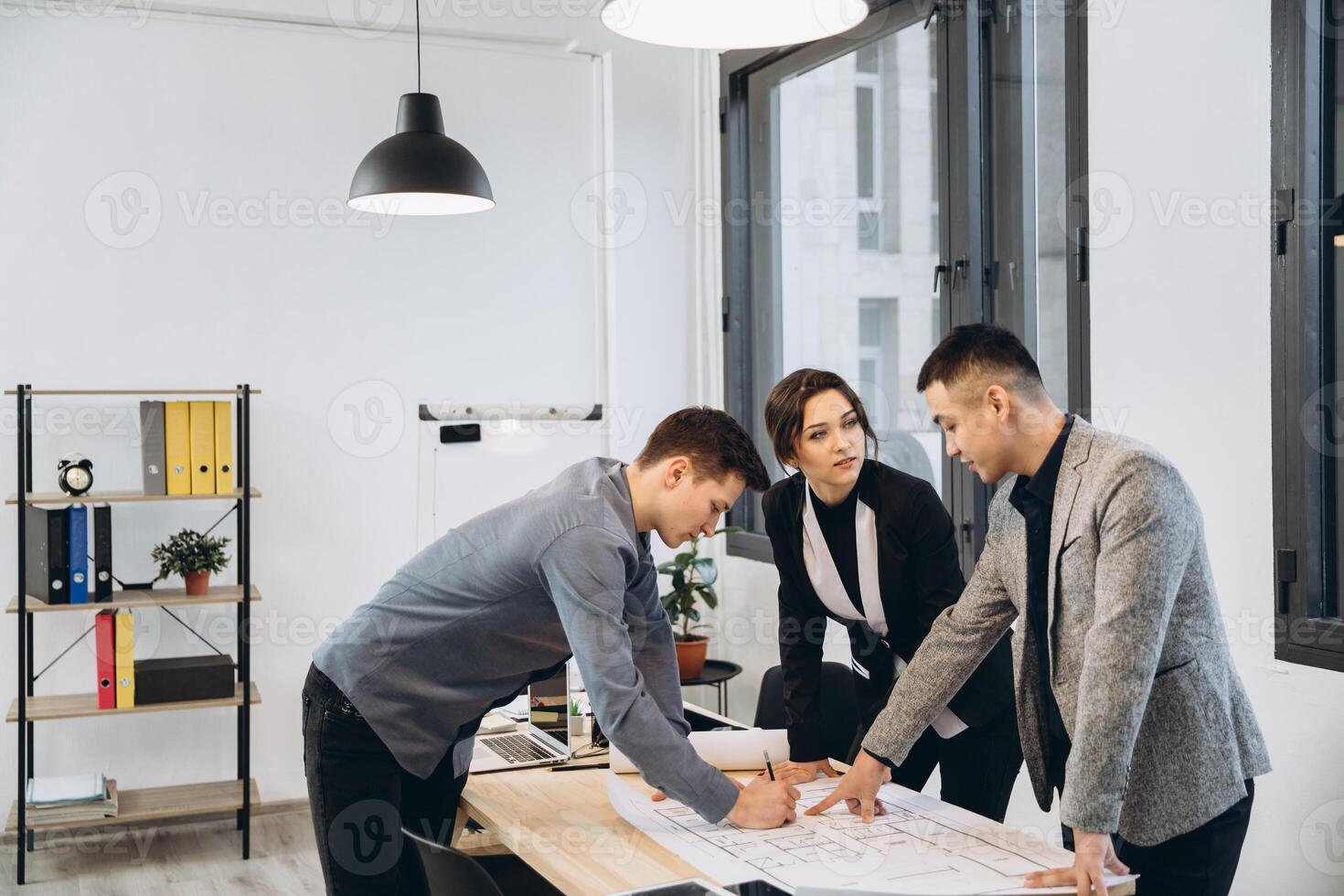 Close-up shot of group of architects drawing building plan together at office photo