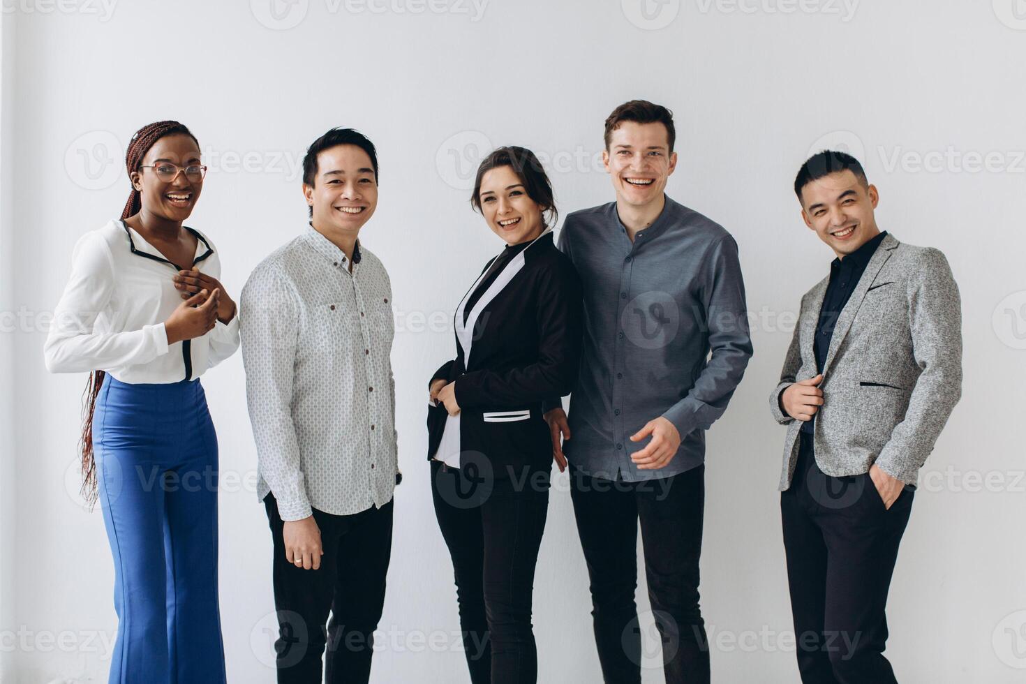 Cheerful multiracial professional business people laughing together standing in row near wall, happy diverse young employees students group, corporate staff team having fun, human resource concept photo