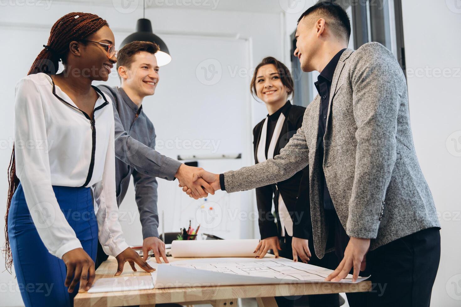 Diverse businessmen shaking hands after signing contracts at group multiracial meeting, african, caucasian and asian partners in suits handshaking promising good deal after successful negotiations photo