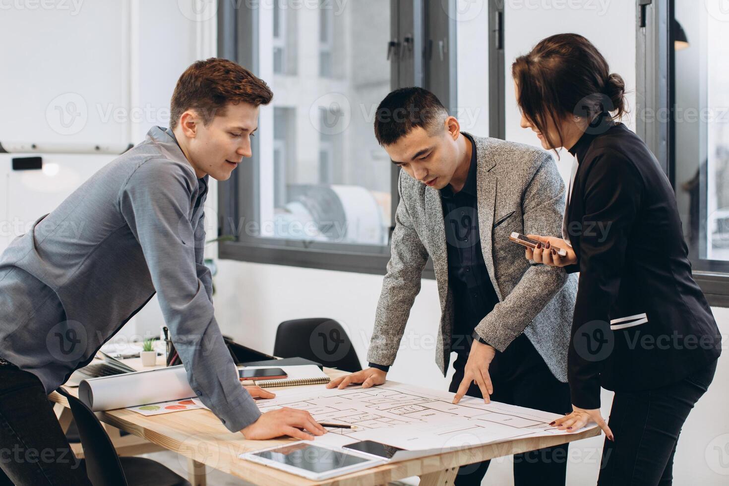Close-up shot of group of architects drawing building plan together at office photo