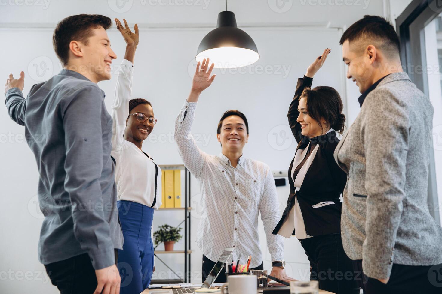 Multiracial euphoric business team people give high five at office table, happy excited diverse work group engaged in teambuilding celebrate corporate success win partnership power teamwork concept photo