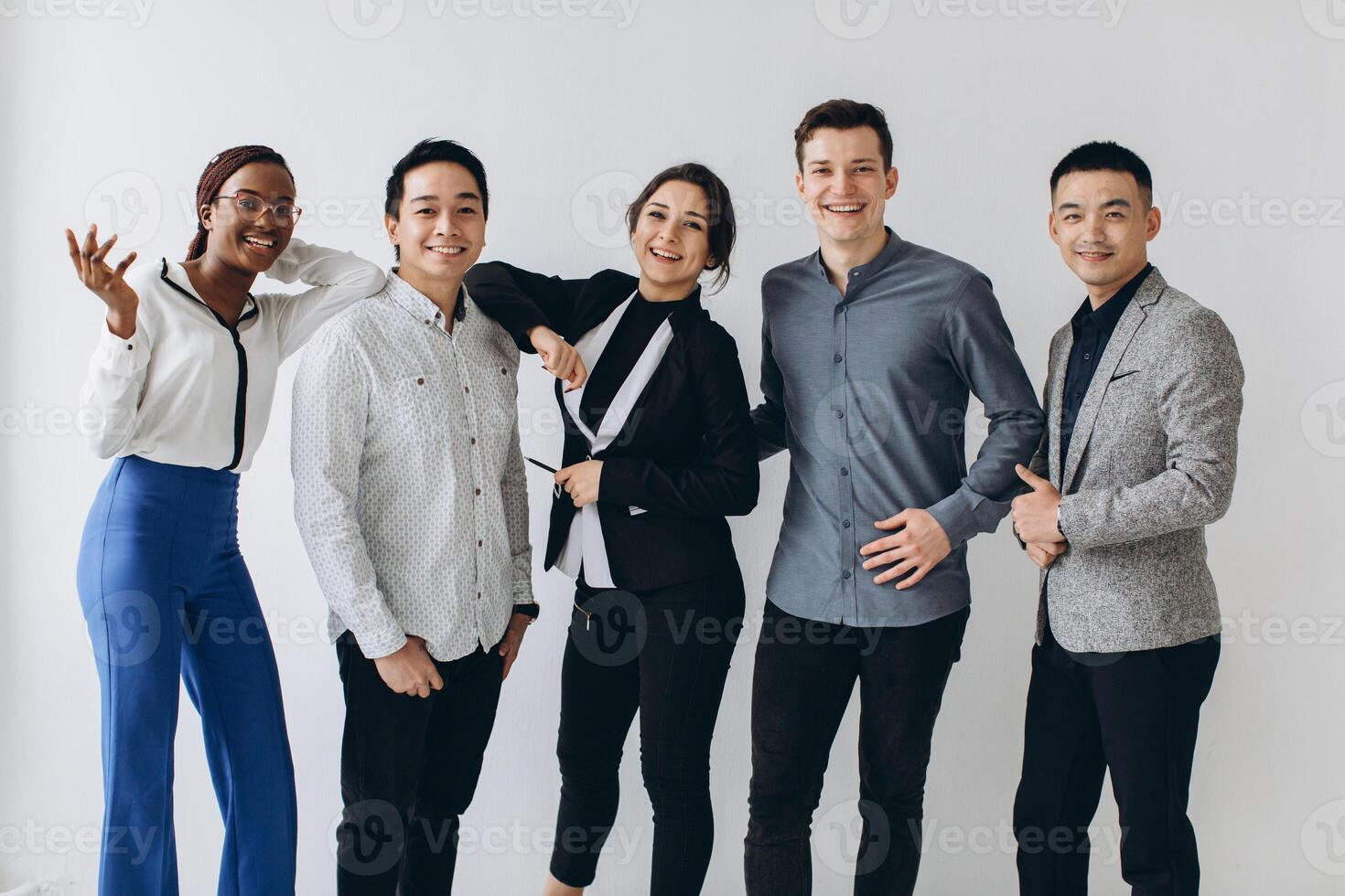 Cheerful multiracial professional business people laughing together standing in row near wall, happy diverse young employees students group, corporate staff team having fun, human resource concept photo