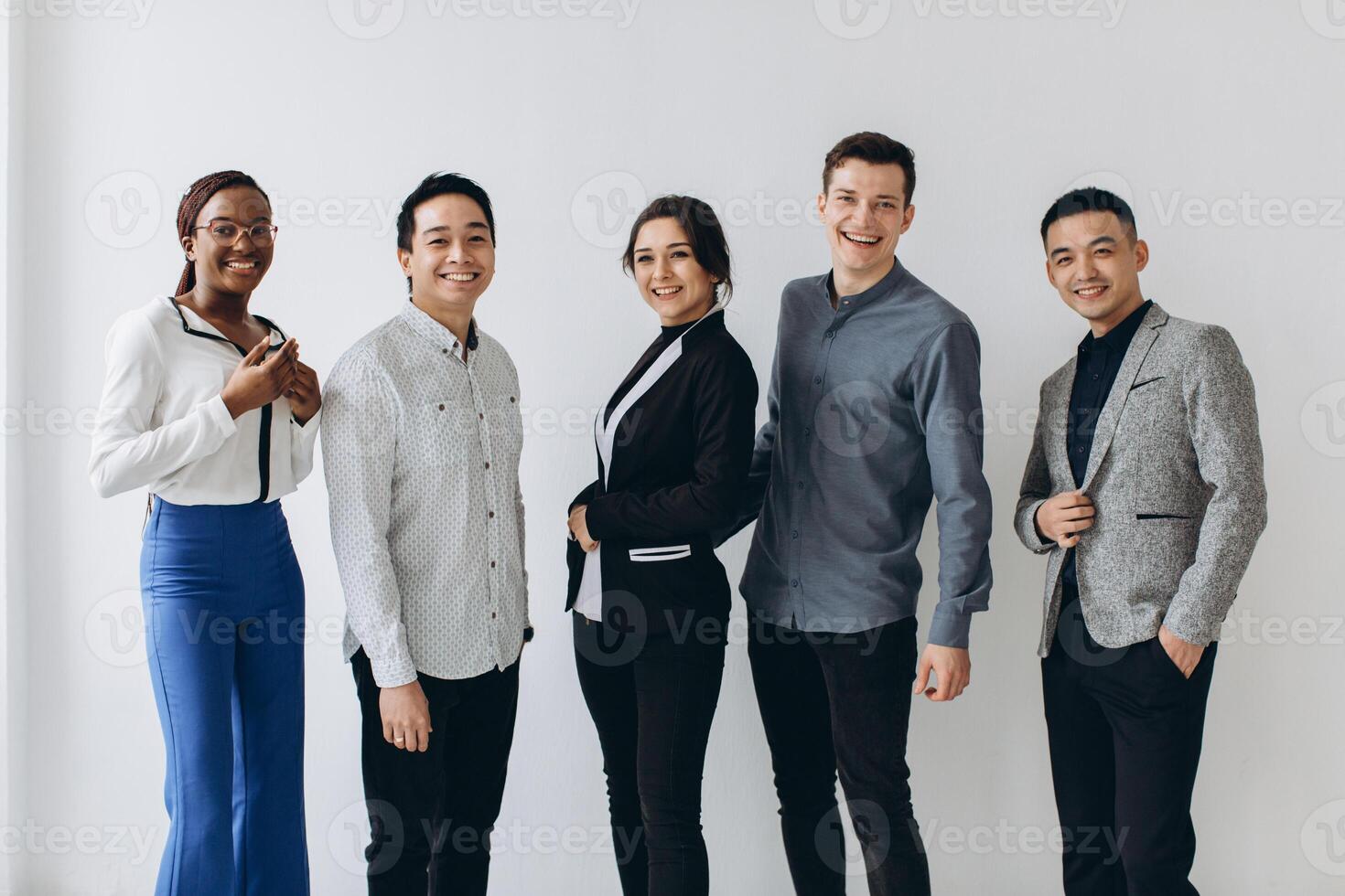 Cheerful multiracial professional business people laughing together standing in row near wall, happy diverse young employees students group, corporate staff team having fun, human resource concept photo