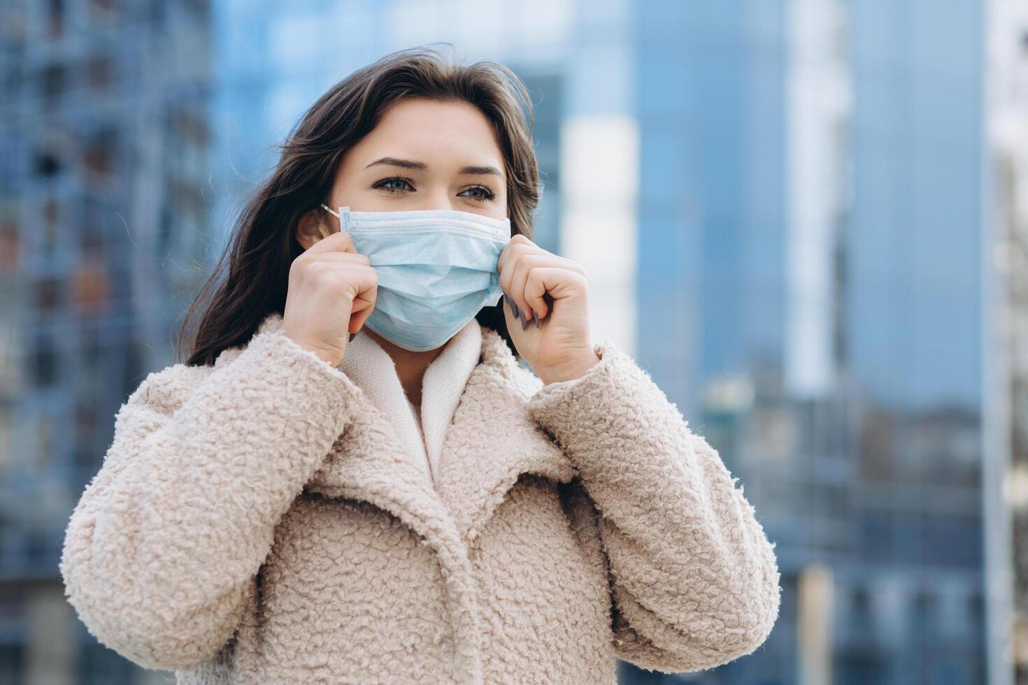Female wearing medical protective mask outdoors. Health protection prevention during flu virus outbreak, coronavirus COVID-19 epidemic and infectious diseases in the city photo