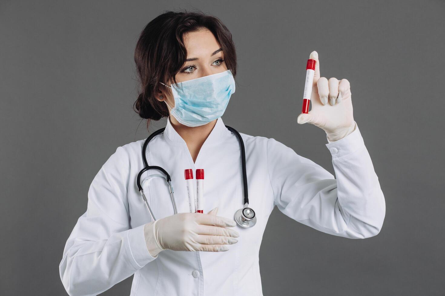A female doctor in a mask holds test tubes, blood tests, potentially infected people with a coronavirus. photo