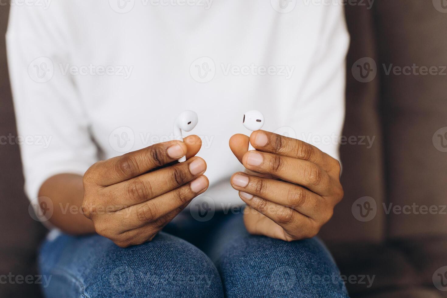 Black woman holding wireless earphone or headphones for using with smartphone. Technology concept photo