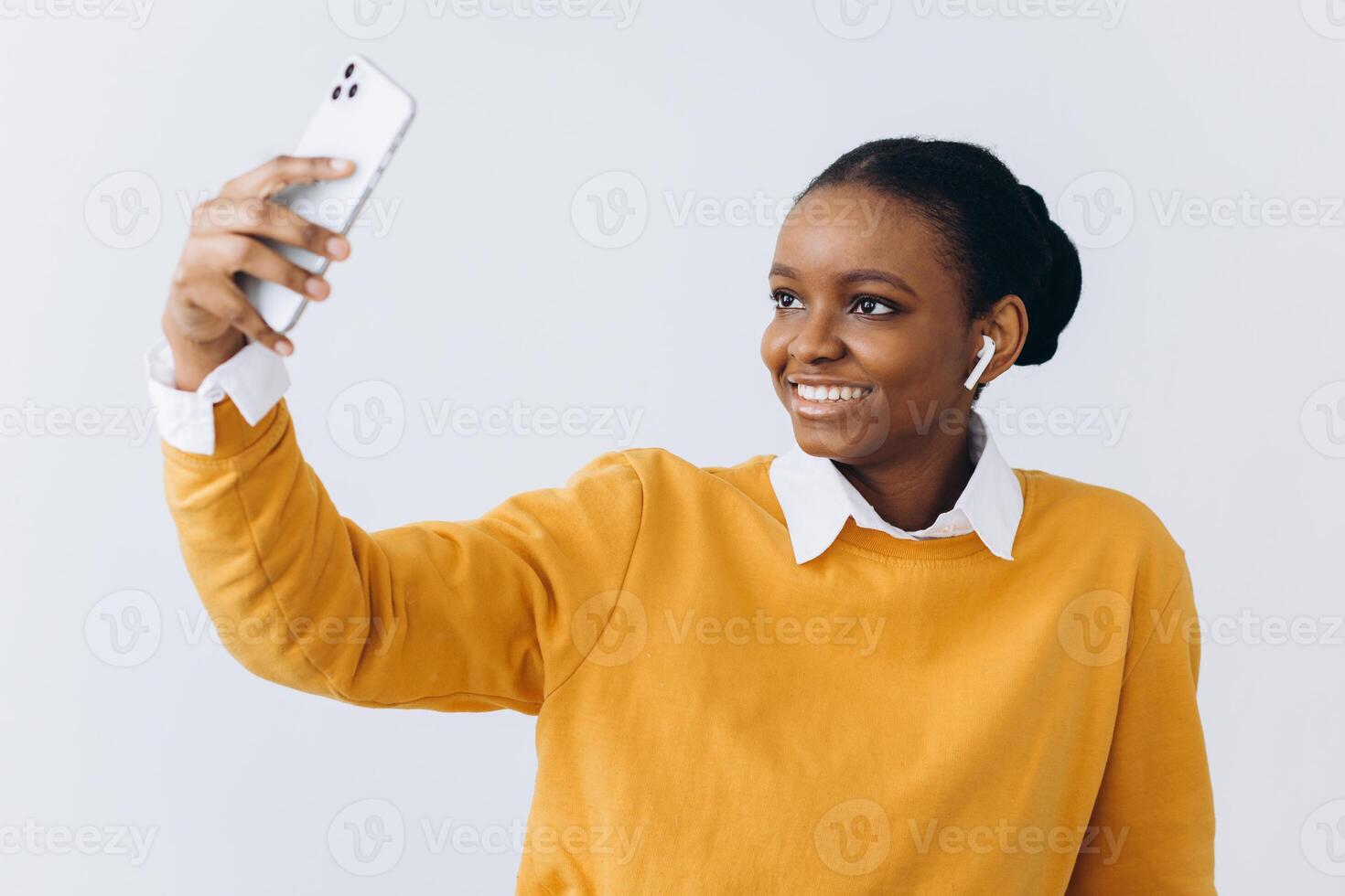 Cute young black lady with stylish dreadlocks taking selfie on smartphone for social media or friends, positive african american woman having fun at home, using mobile phone, copy space photo