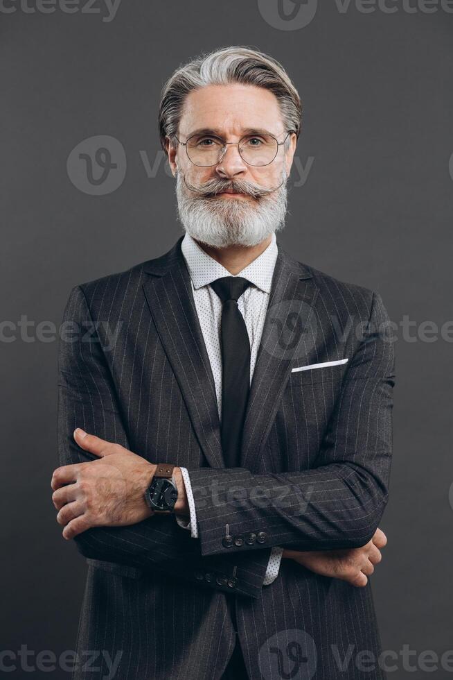 Portrait of a stylish and fashionable mature man in a gray suit. Business and trendy close-up concept on the grey background. photo