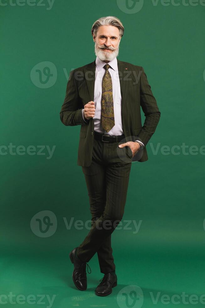 Stylish bearded middle-aged man in khaki suit on green background photo