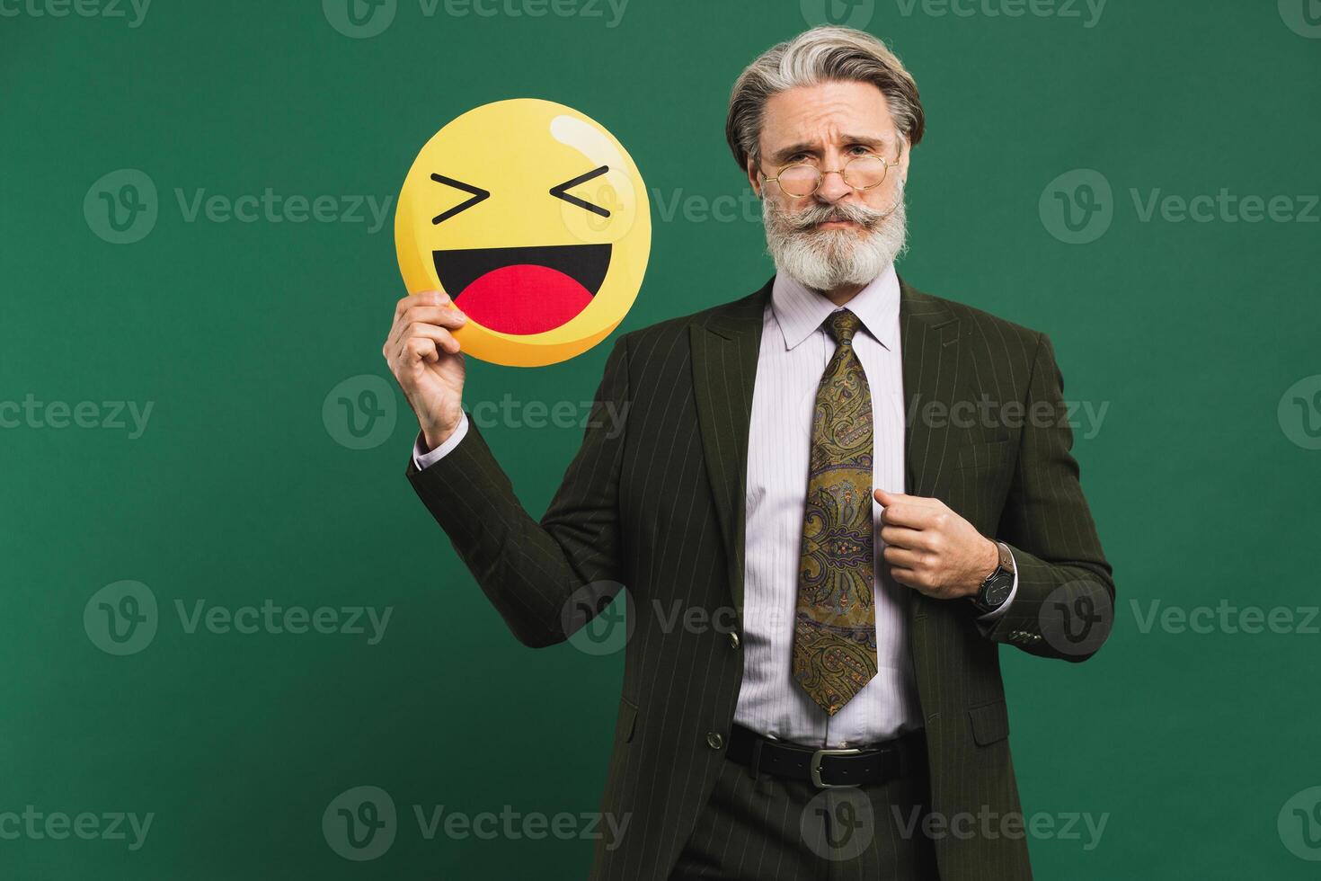 Business middle-aged bearded man in khaki suit holding emoji with smile on a green background photo