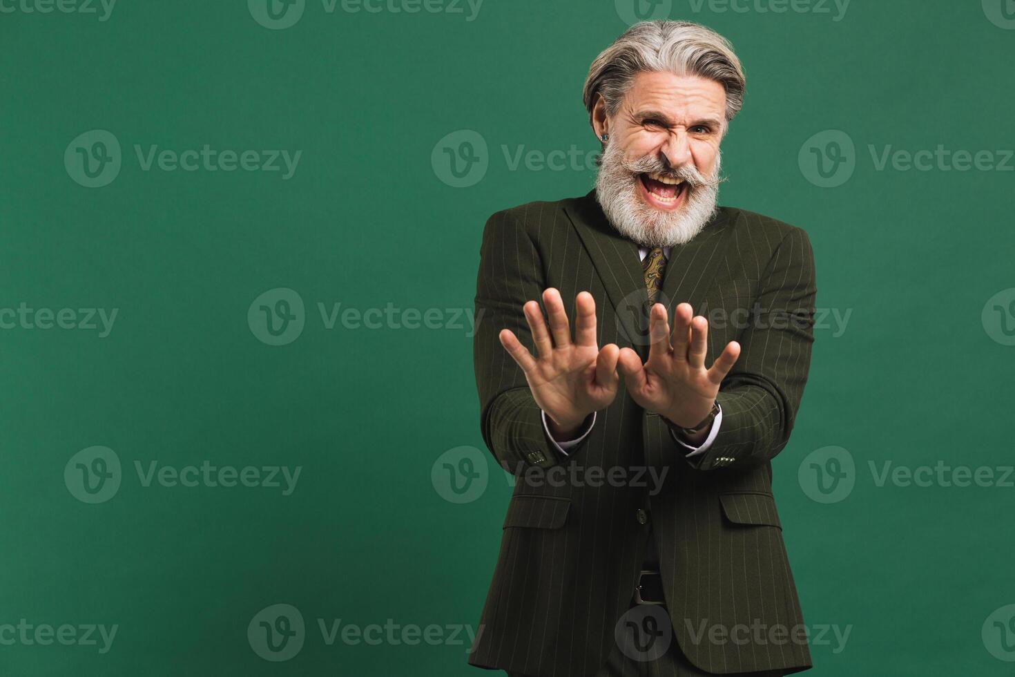 A middle-aged bearded man in khaki costume shows with his hands and says no against a green background photo