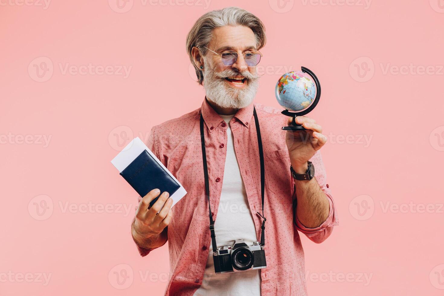 Happy bearded man in sunglasses with a camera and passport chooses a country on a globe for travel. photo