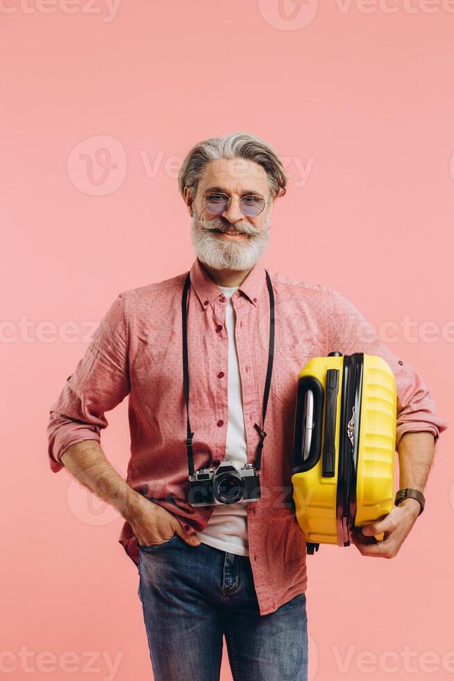 A bearded man holds a yellow suitcase, smiles and prepares for the trip. photo