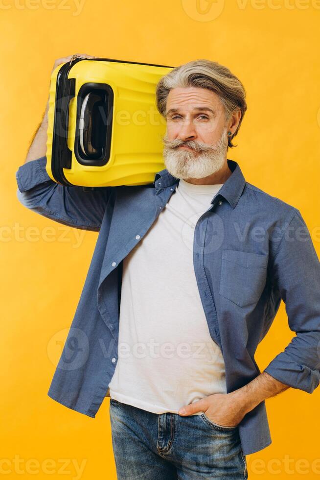 Stylish laughing bearded man holding a yellow suitcase. photo