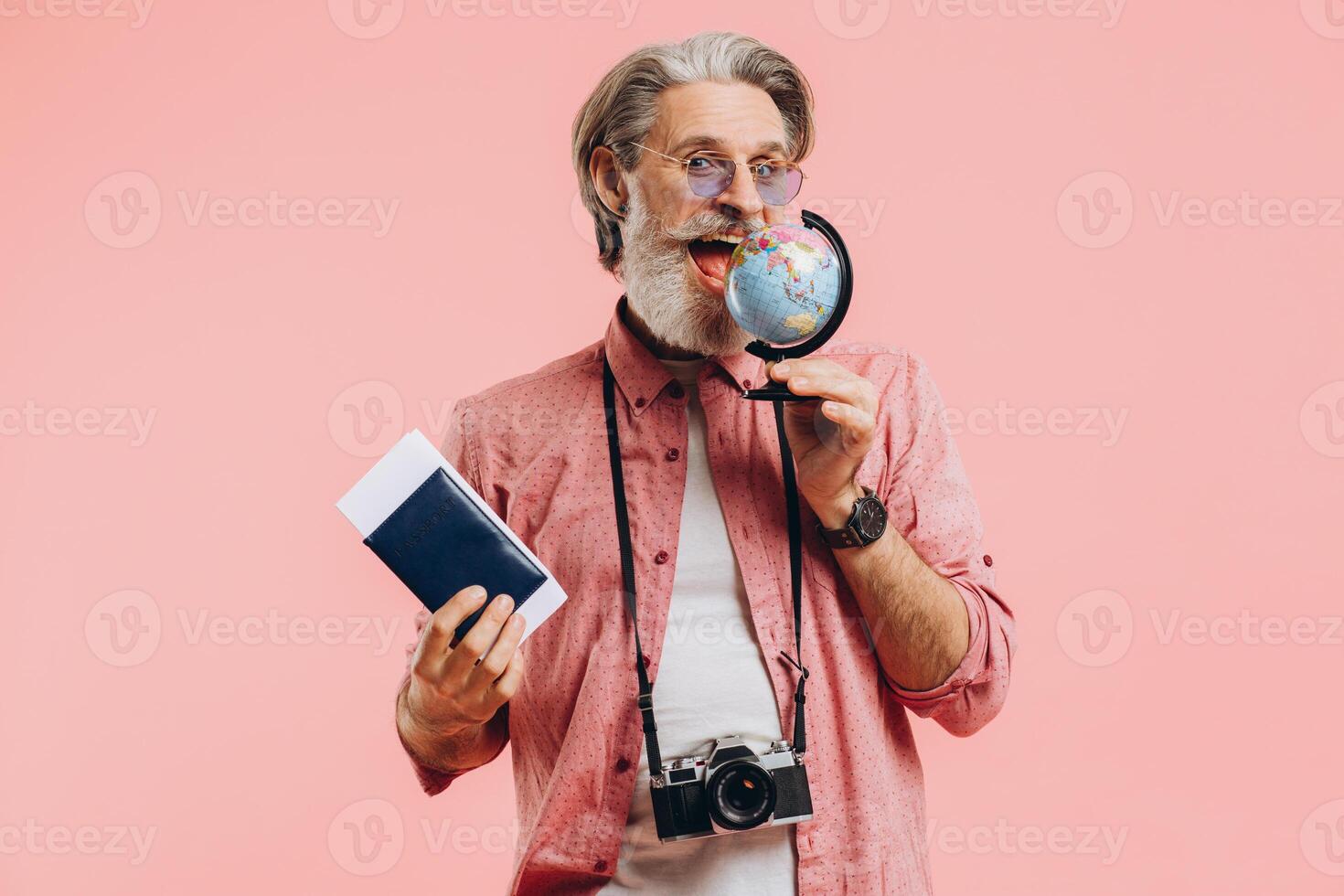 Happy bearded man in sunglasses with a camera and passport chooses a country on a globe for travel. photo