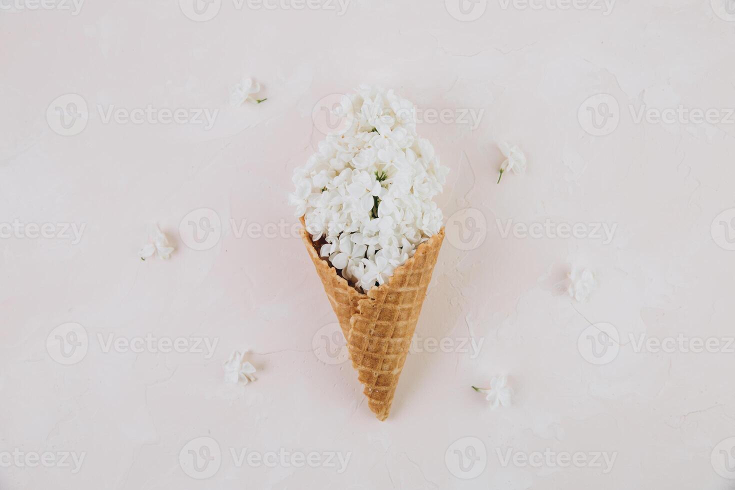 Waffle cone with lilac flower bouquet on marble background. Flat lay, top view, floral and spring composition photo