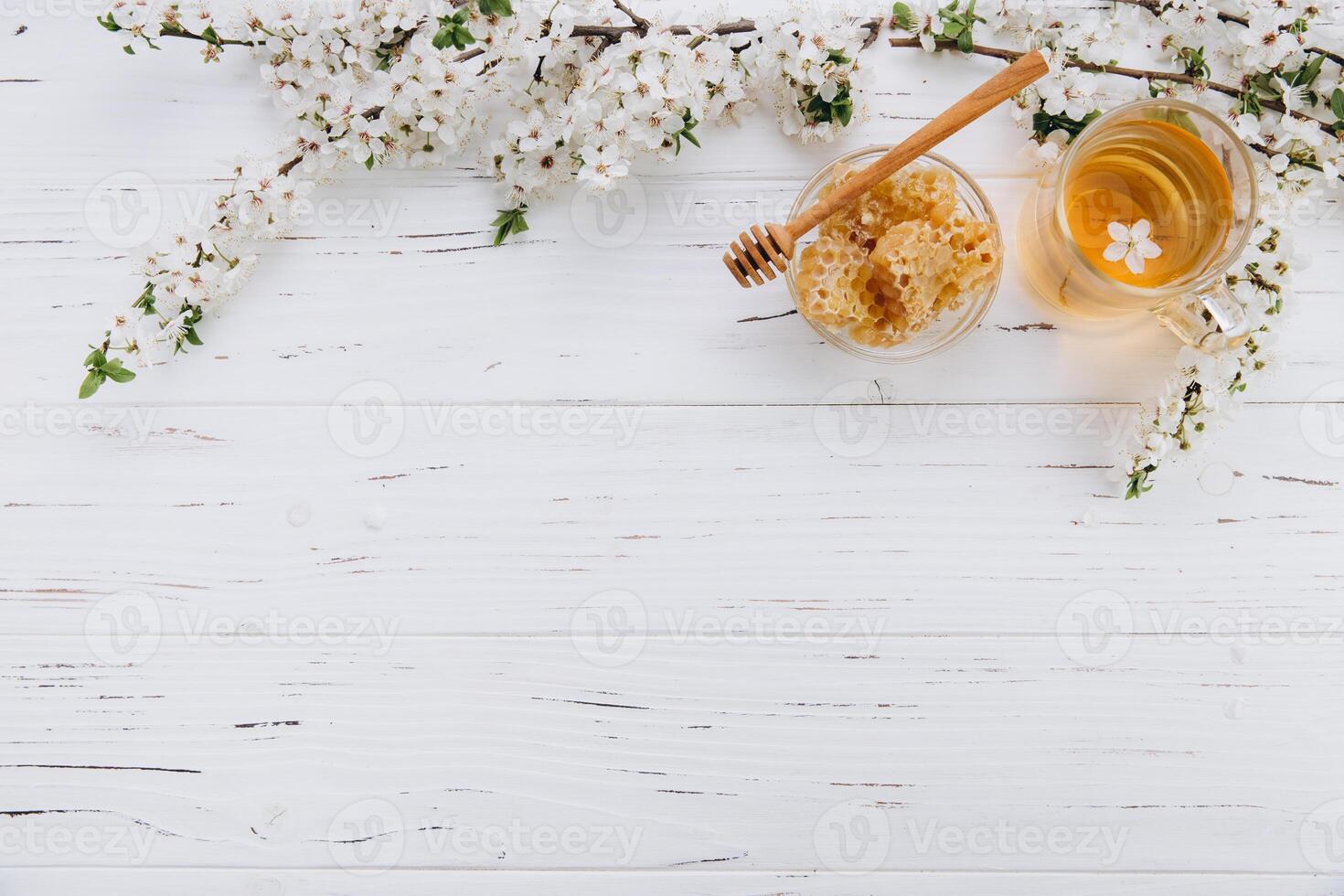 Spring composition. A cup of herbal tea and a jar of honey on a white wooden background, cherry flowers top view. Place for text. Healthy food concept. photo