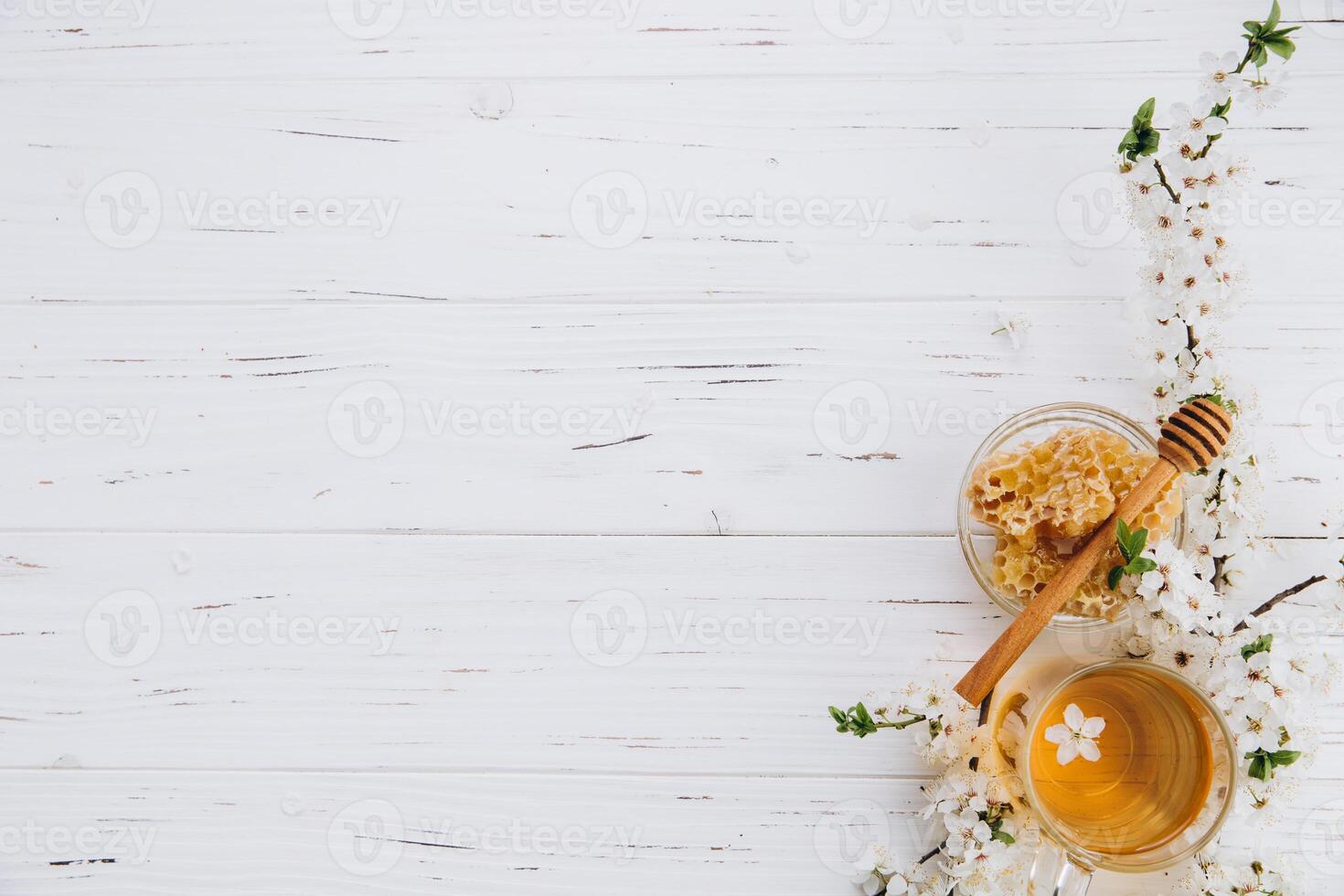 Spring composition. A cup of herbal tea and a jar of honey on a white wooden background, cherry flowers top view. Place for text. Healthy food concept. photo