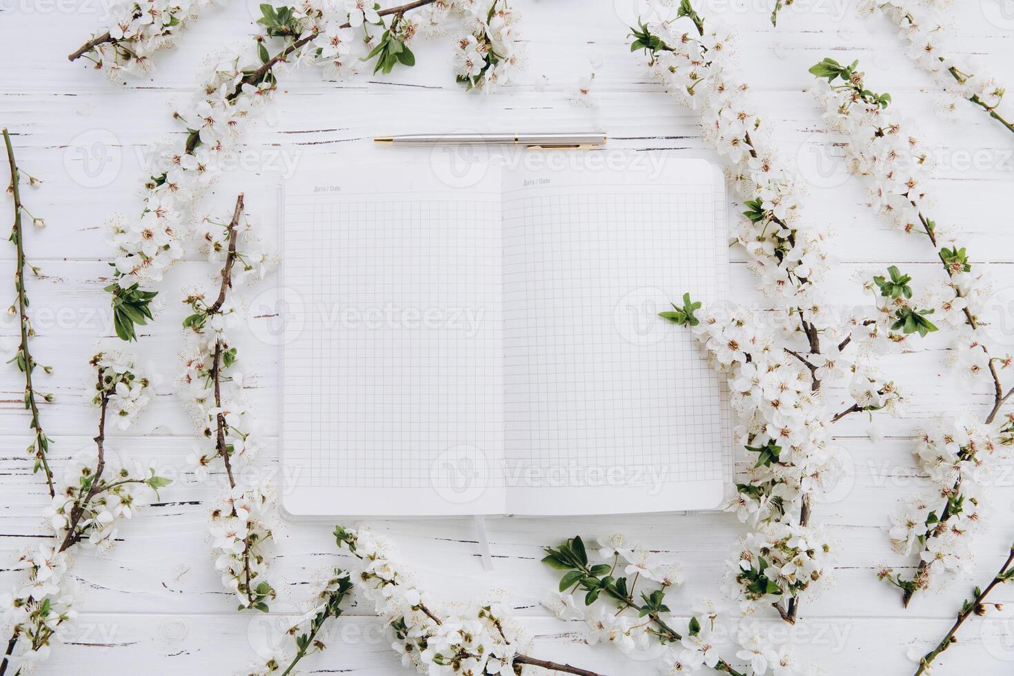 Spring flowers - cherry blossom, empty notebook on white wooden table. Ideas, notes, goals or plan writing, birthady, invitation concept. Top view, flat lay. photo