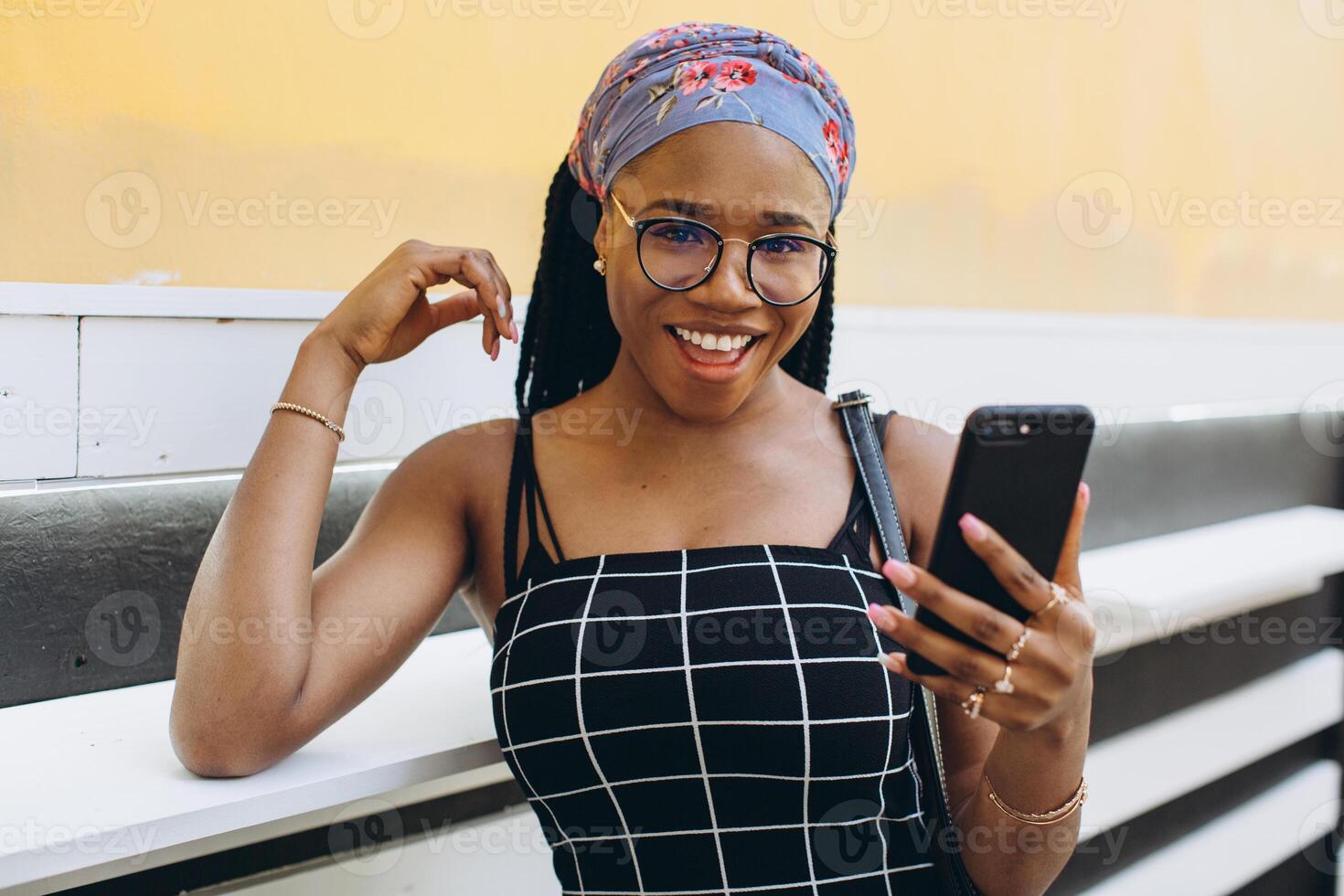 Pretty African American woman in a dress has fun outside and talks by phone photo