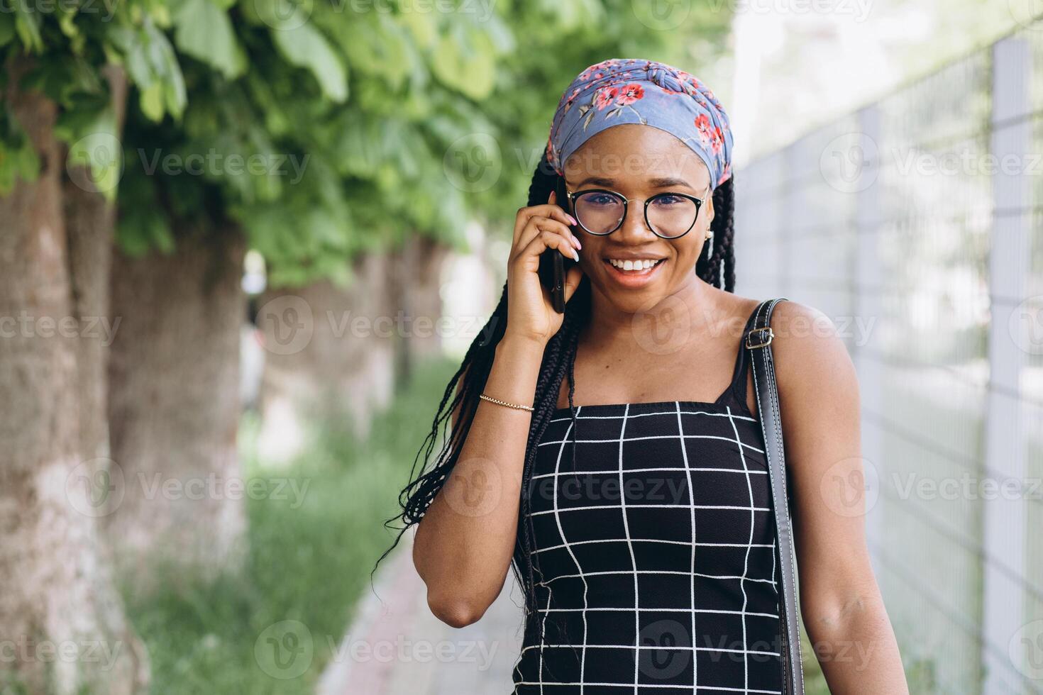 Pretty African American woman in a dress has fun outside and talks by phone photo
