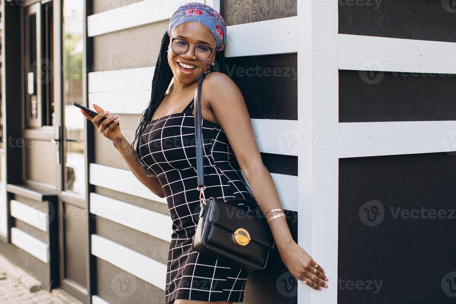 Pretty African American woman in a dress has fun outside and talks by phone photo