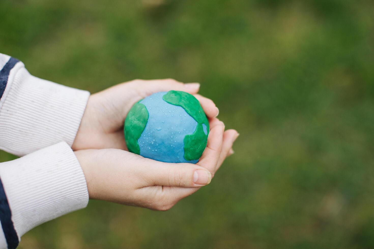 Female hands holding Earth in hands against green spring background. photo