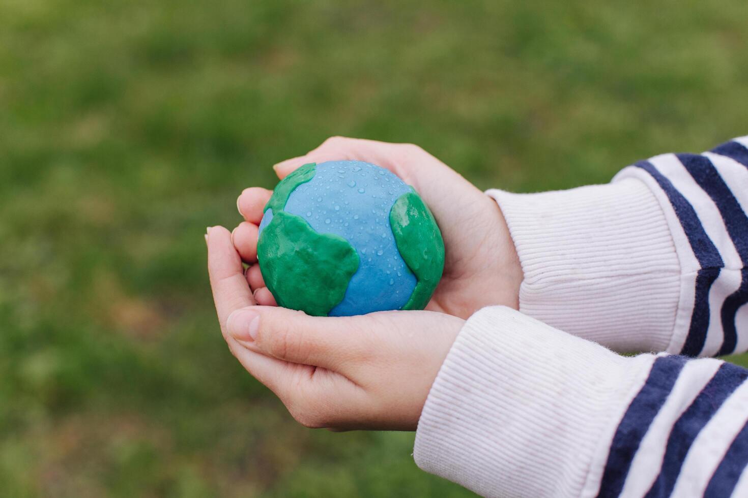 Female hands holding Earth in hands against green spring background. photo