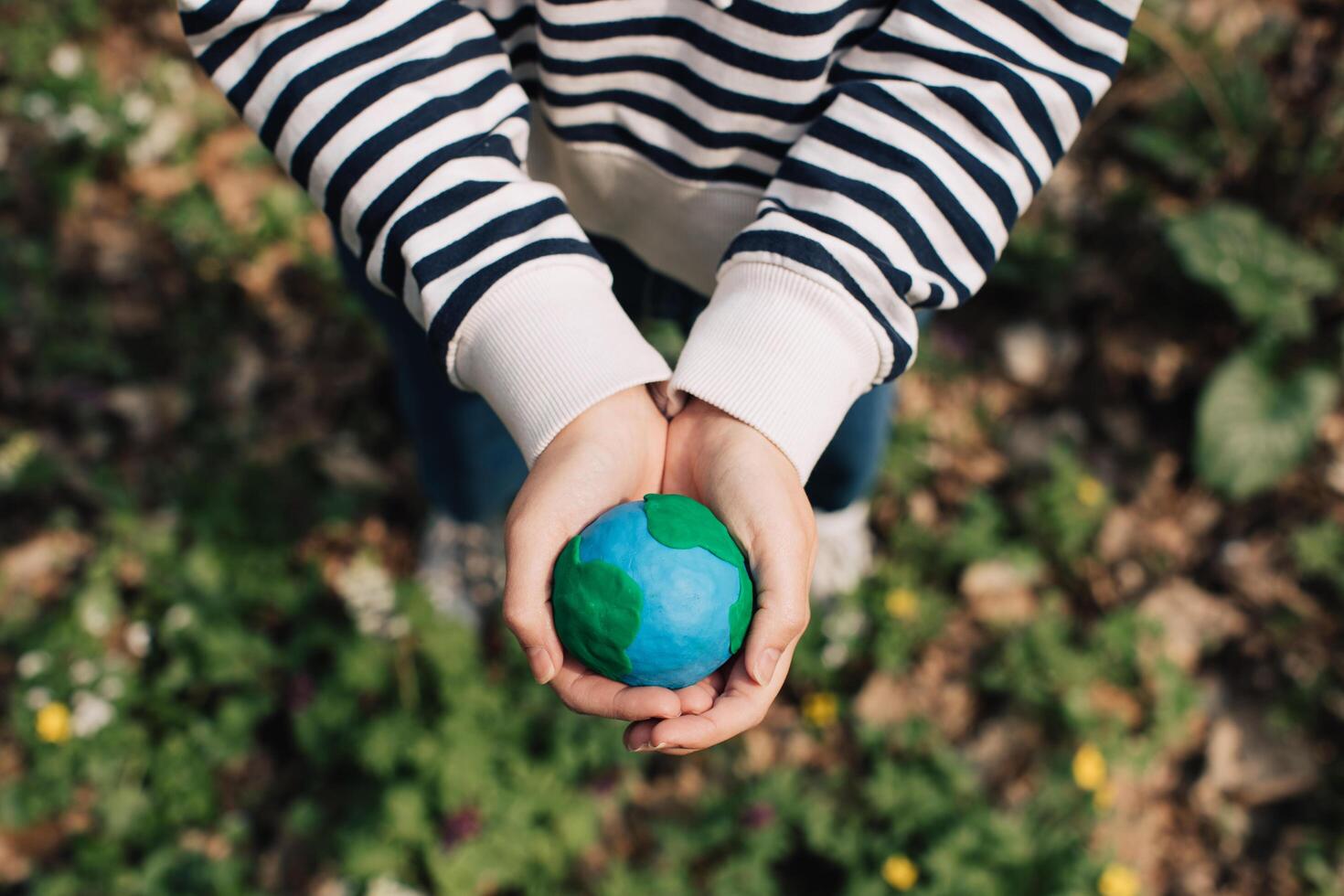 Female hands holding Earth in hands against green spring background. photo
