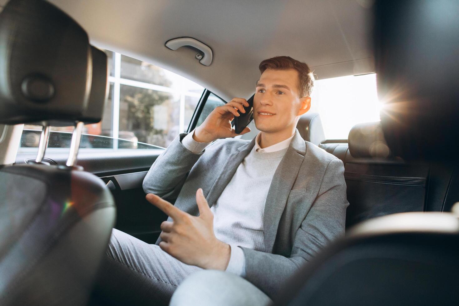 Young businessman talking on a mobile phone while sitting in the back seat of a car. photo