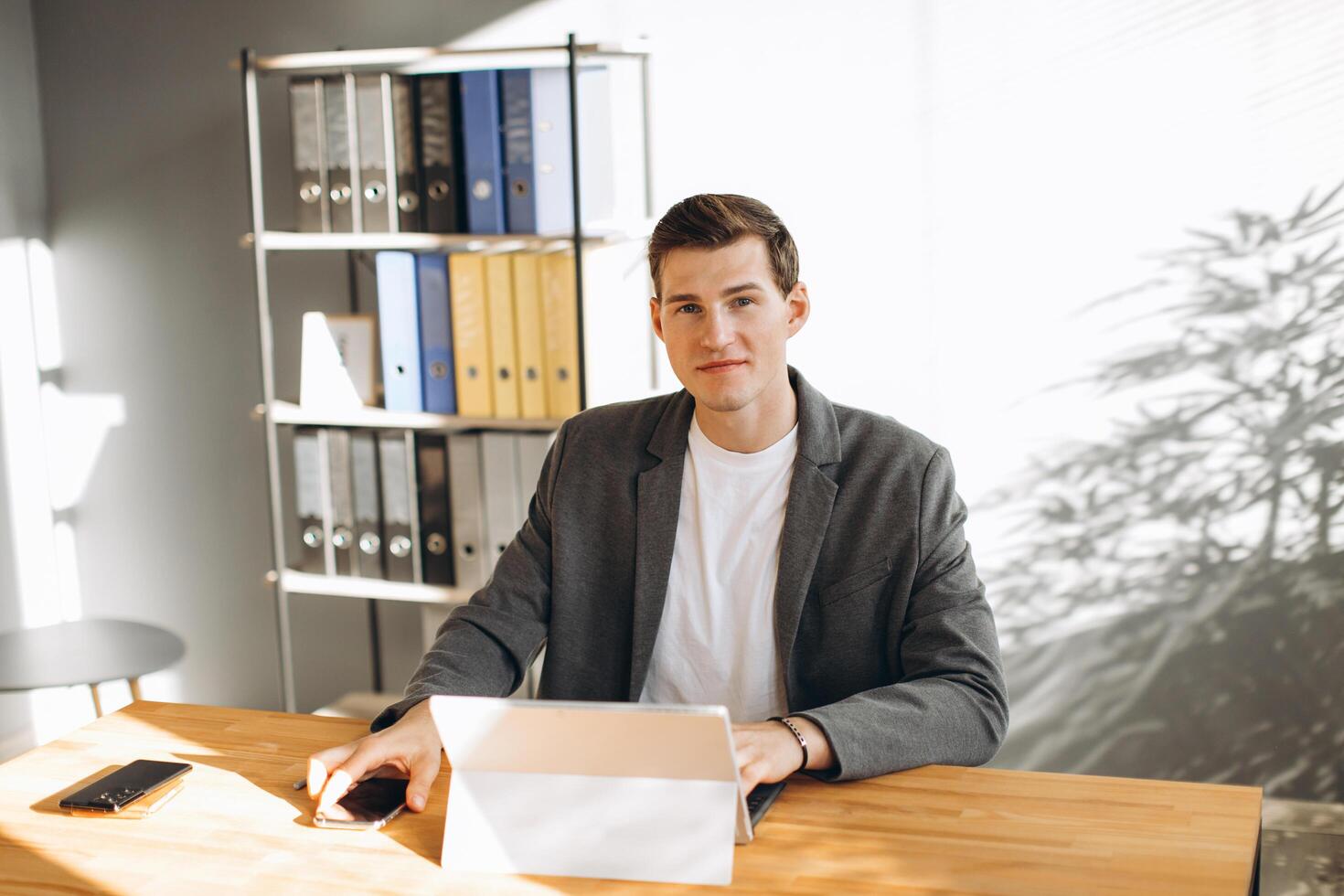 Modern smiling man, office worker working in the office at the computer photo