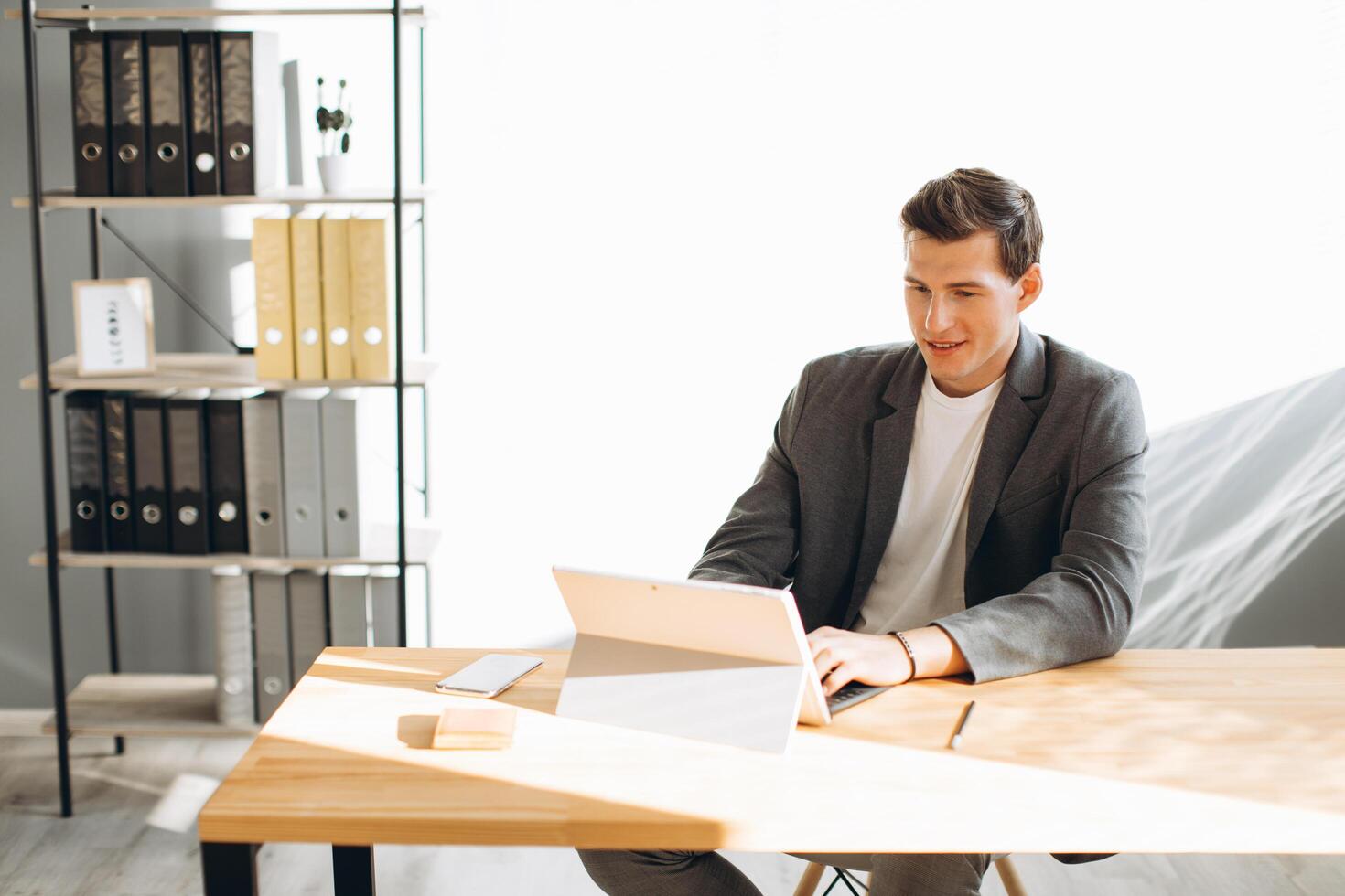 Modern smiling man, office worker working in the office at the computer photo