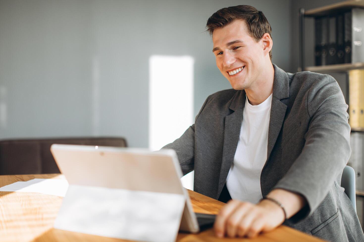 Modern smiling man, office worker working in the office at the computer photo