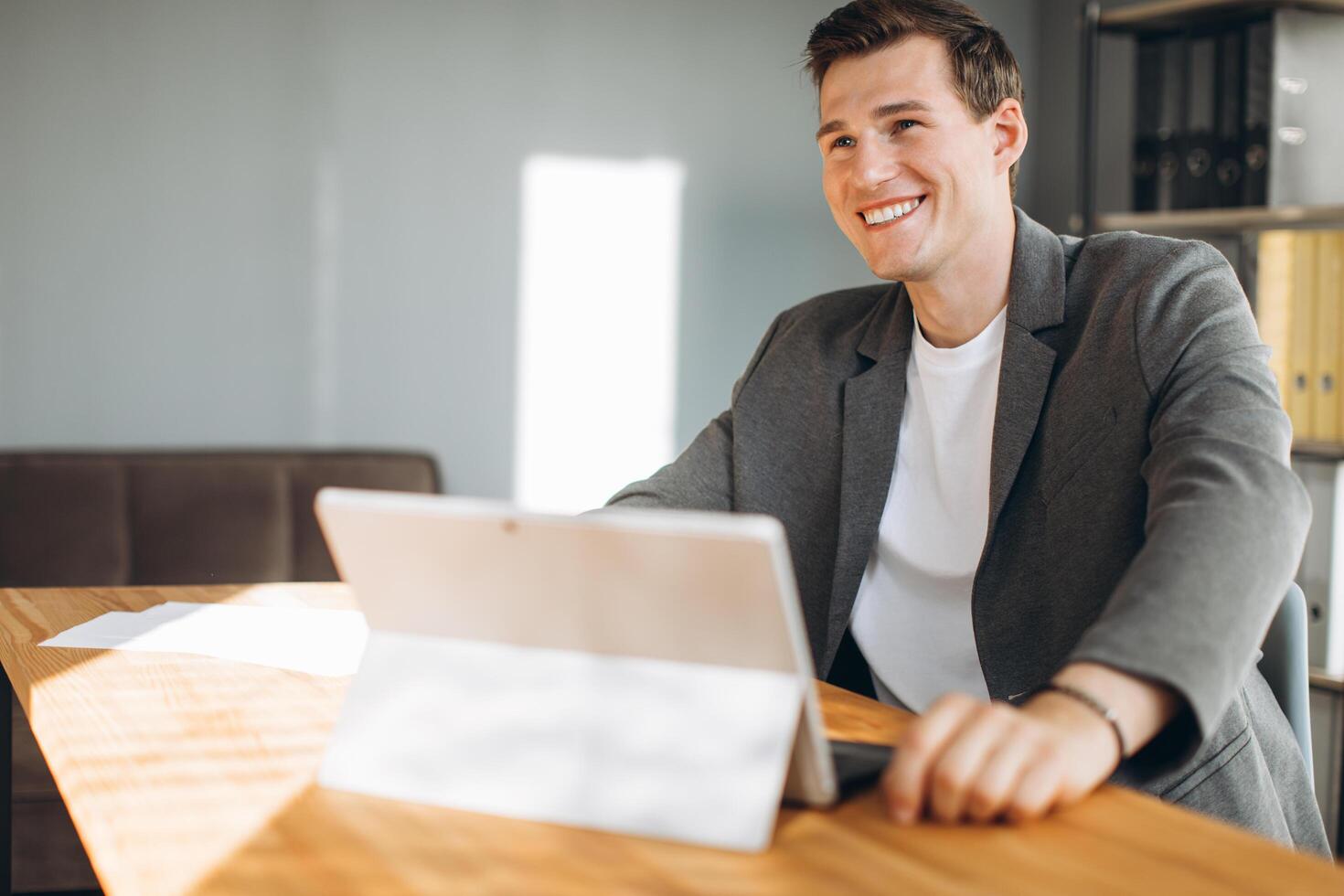 Modern smiling man, office worker working in the office at the computer photo