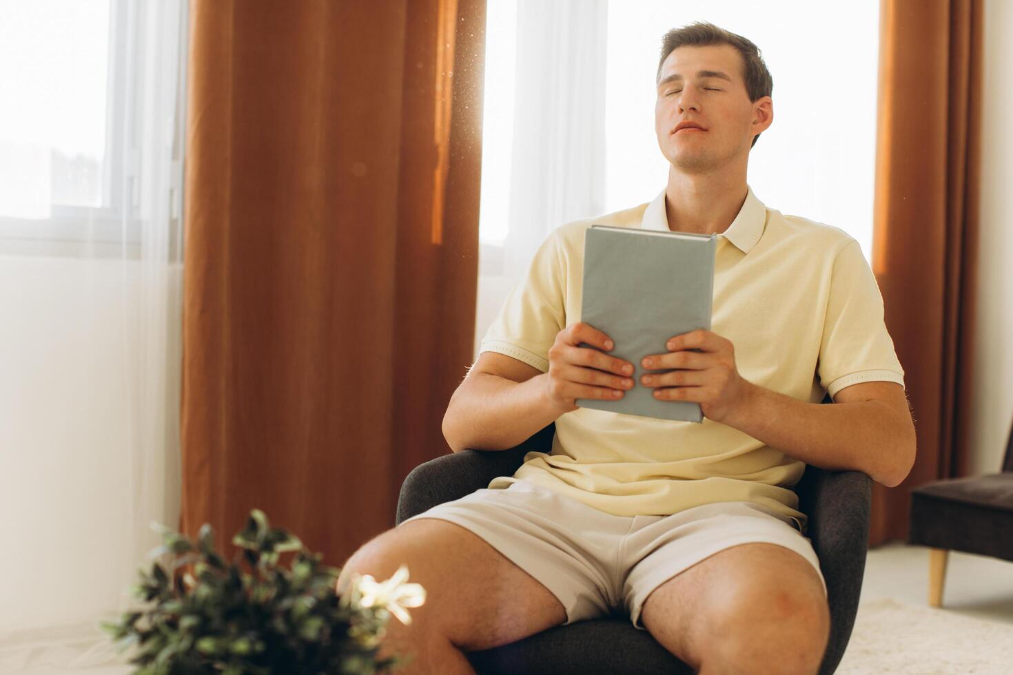 A handsome boy is sitting on a chair at home holding a bible photo