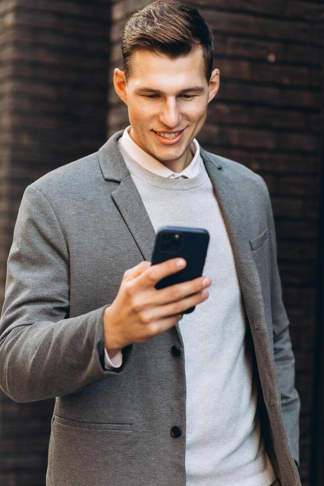 Modern handsome smiling man walking down the street and talking on the phone photo
